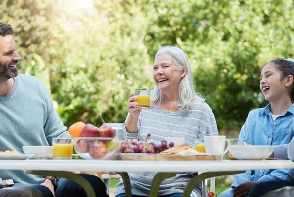 Family sharing a meal together at a table in their back yard