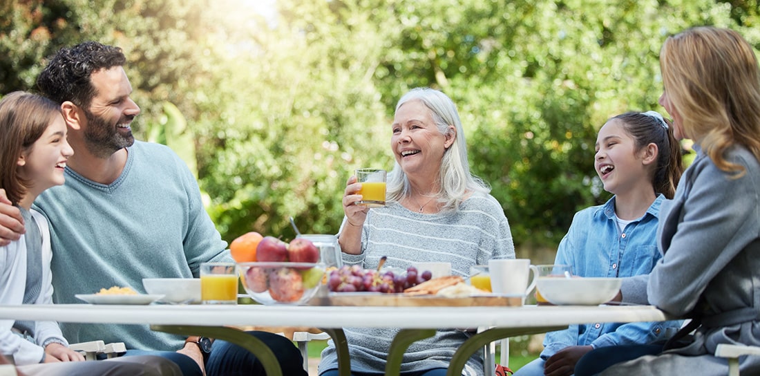 Family sharing a meal together at a table in their back yard